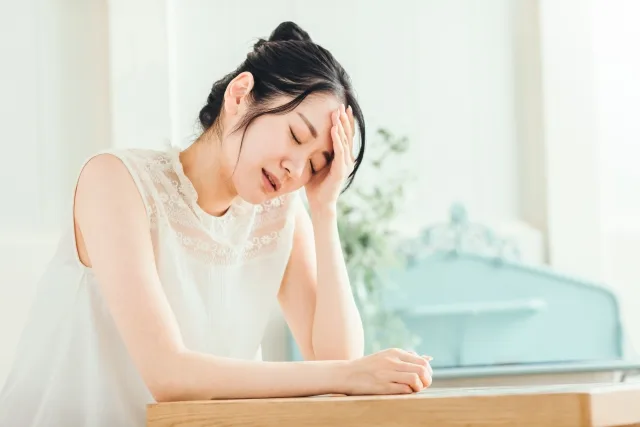 頭に手を置いて悩んでいる女性