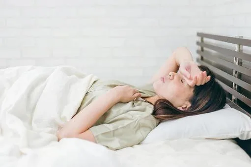 仰向けで頭痛を感じる女性