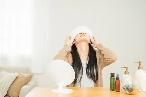 ホットタオルで目を休める女性