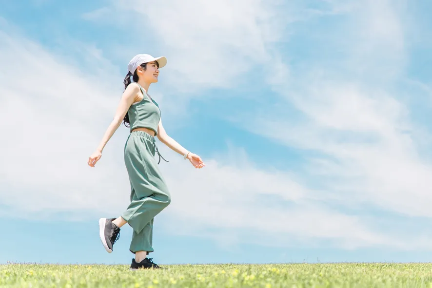 青空の下ウォーキングする女性
