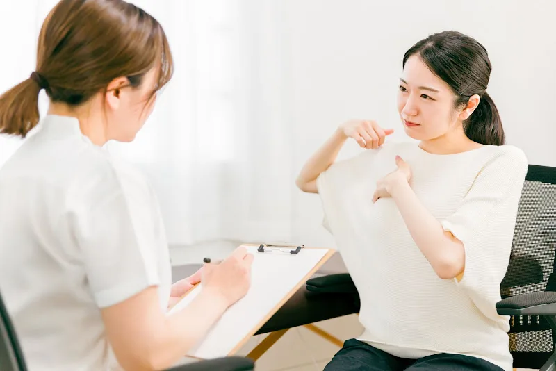 肩の不調を整体師に相談する女性