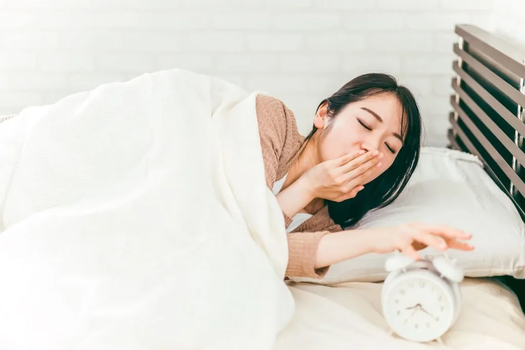 ベッドであくびをする女性