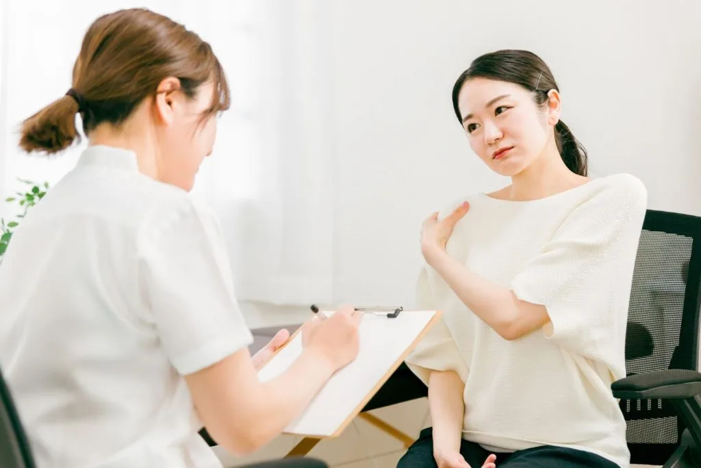 肩の不調を相談している女性