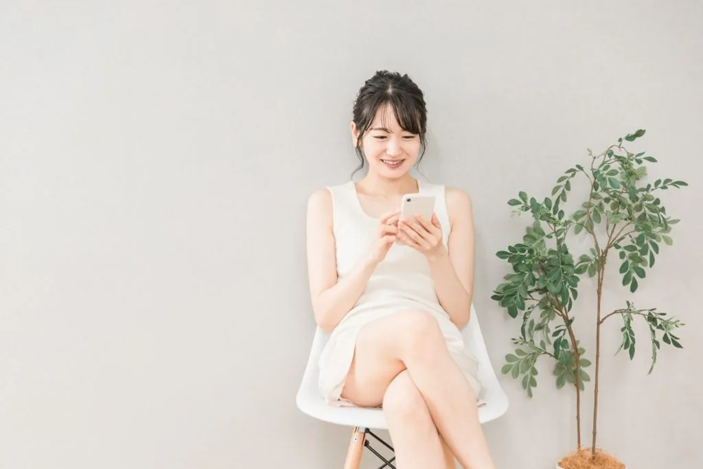 スマホを両手で操作している女性
