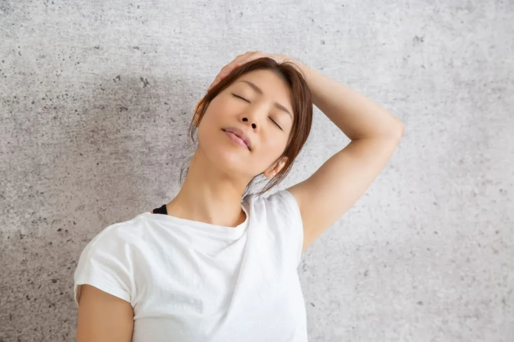 頭を押さえて首を伸ばす女性