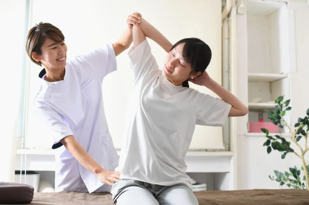 整体師とストレッチの補助をしてもらう女性