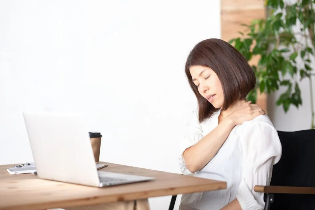 デスクワークで肩こりに悩む女性