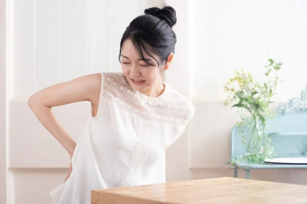 腰に手を当てて痛がる女性
