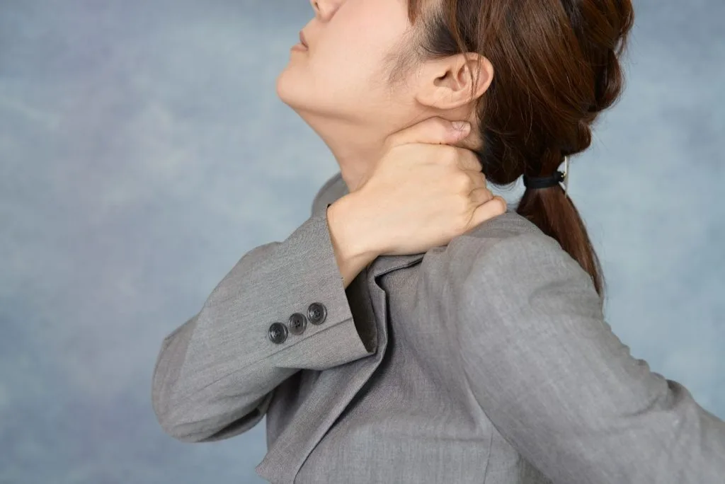 右手で左肩に手を当てる女性