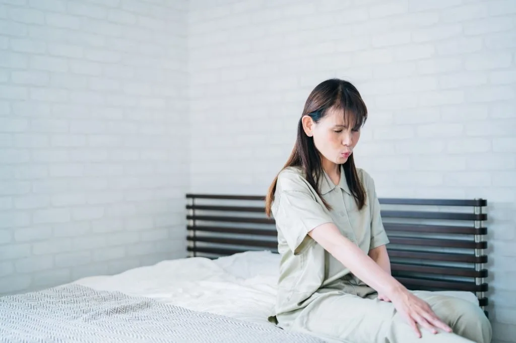 ベットに座って膝を押さえる女性
