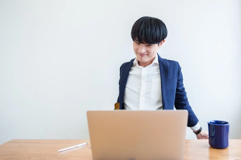 デスクワークをしながら背筋を伸ばす男性