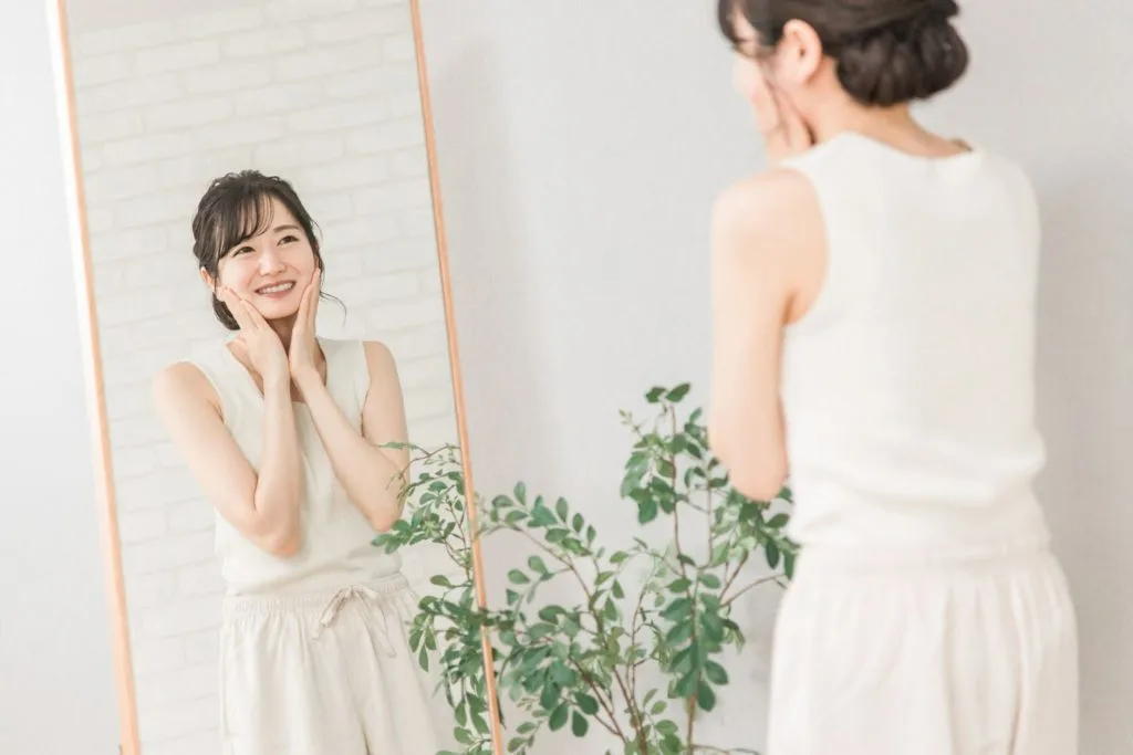 全身鏡で顔の歪みをチェックする女性