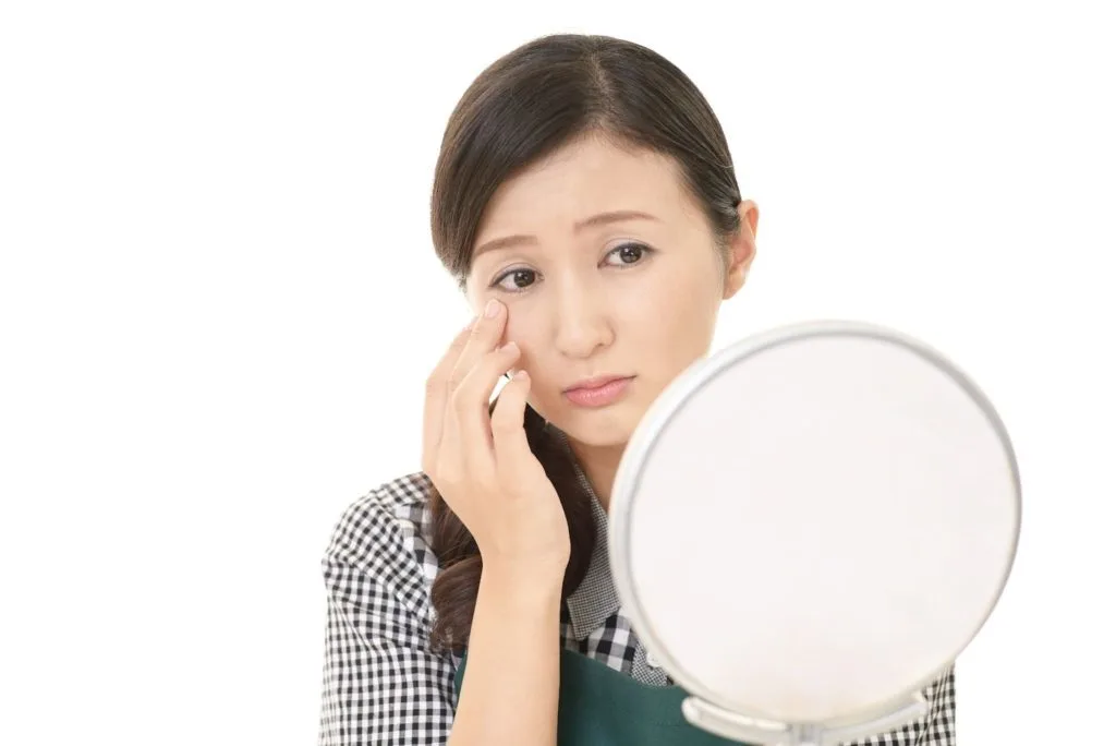 手鏡で顔の歪みをチェックする女性