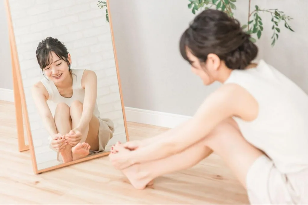 体育座りしながら足の先端のツボをマッサージする女性