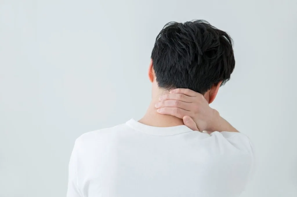 首の後ろ側を手で押さえる男性