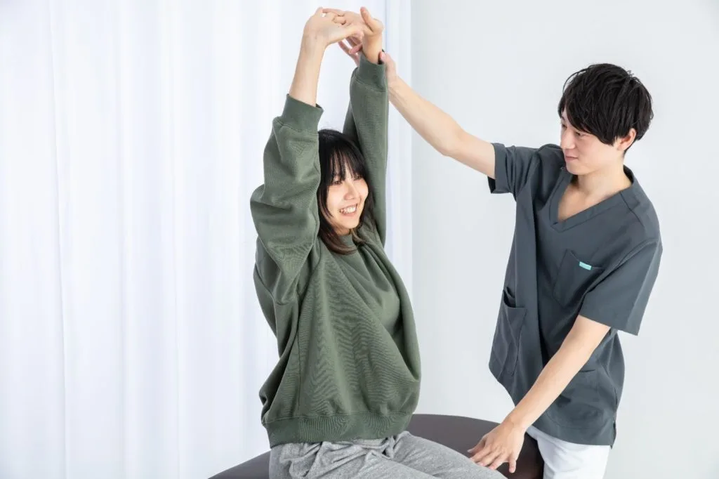 補助してもらいながらストレッチをする女性