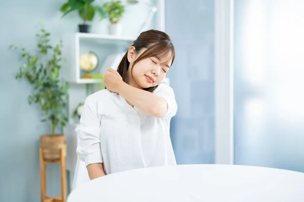 自分の肩を叩いてマッサージする女性