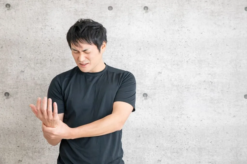 右手首を押さえる男性