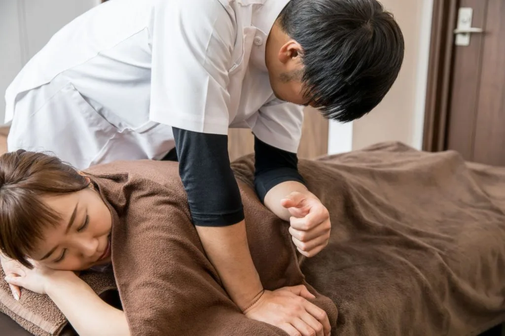 腰をマッサージする整体師