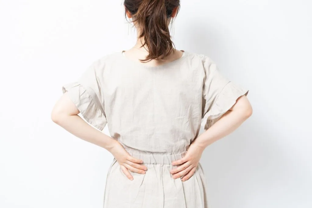 腰に両手を当てる後ろ向きの女性