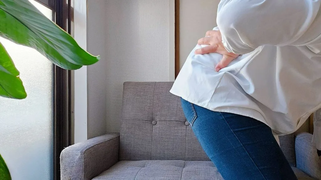 腰の痛みを気にする女性