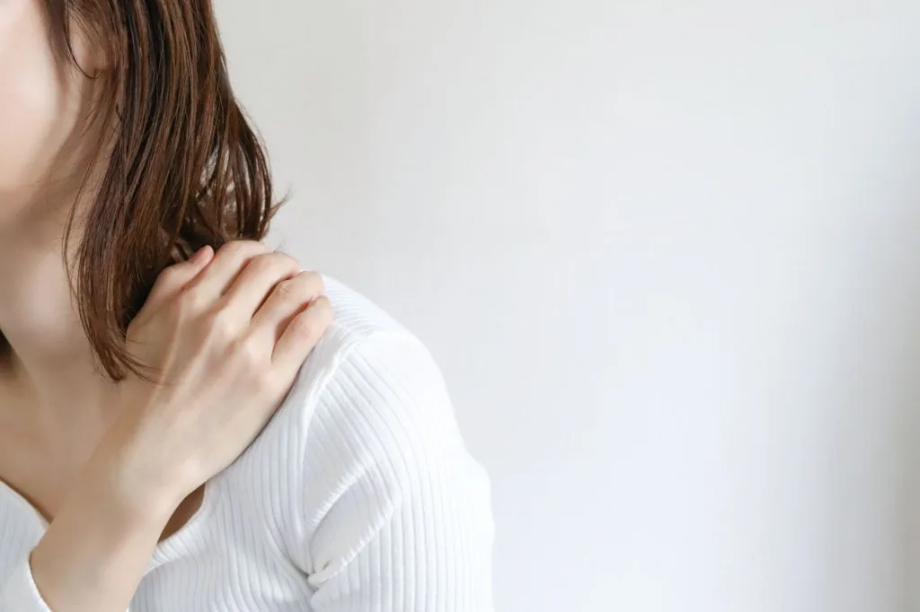 肩の辺りを気にする女性