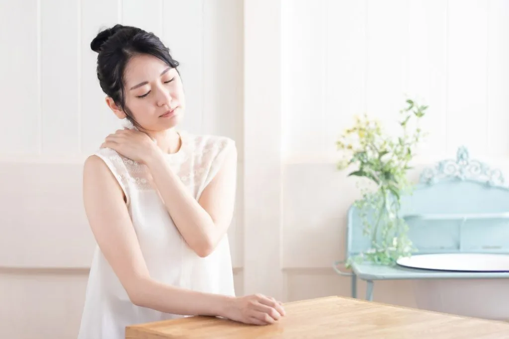 肩の辺りを気にする女性