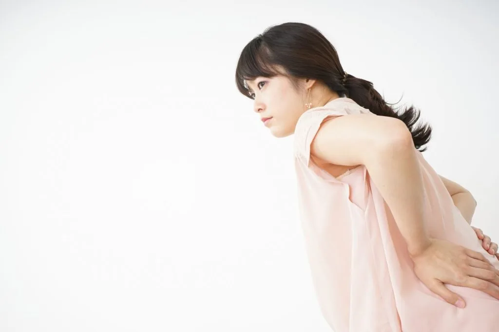 腰の辺りを気にする女性