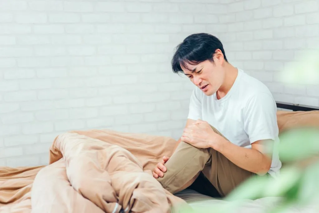 膝を抱えて足を気にする男性