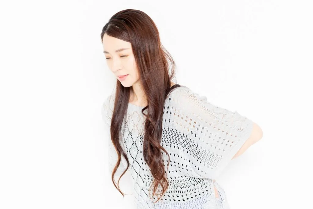 腰の辺りを気にする女性