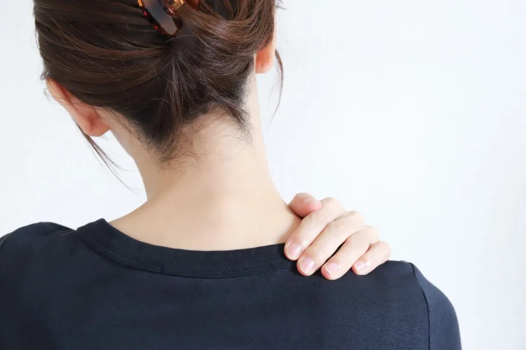 肩の辺りを気にする女性