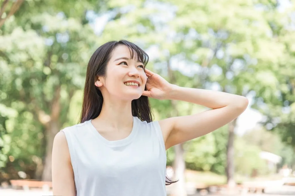 耳の辺りを抑えて笑っている女性