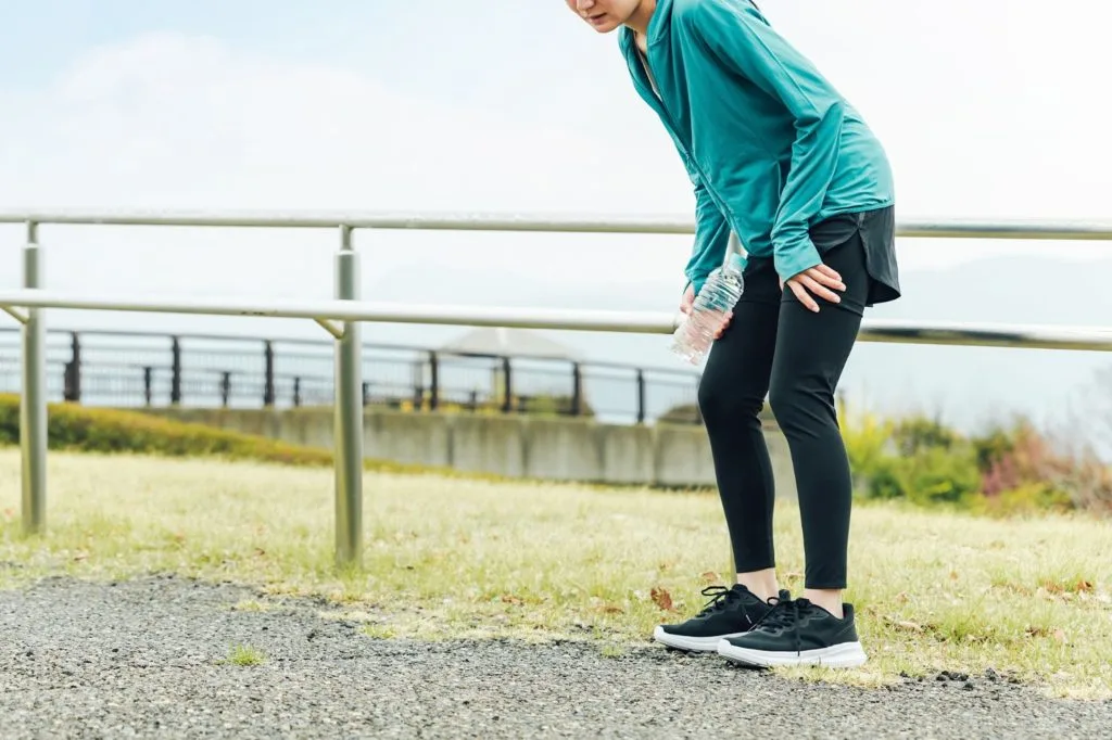 ももの辺りの痛みを感じ、抑える女性